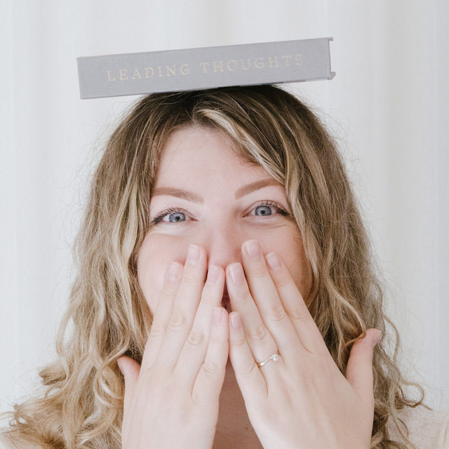 Woman balancing 'leading thoughts' book on her head