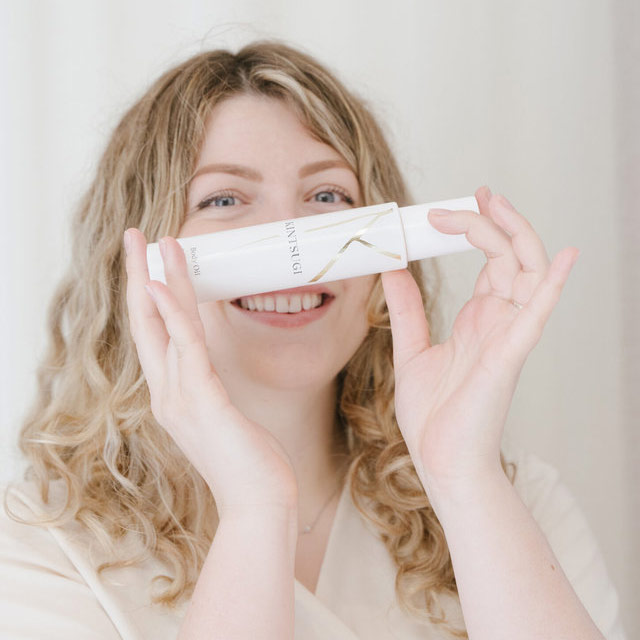 Woman holding body oil in front of her face