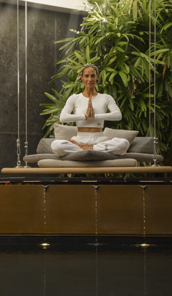 Woman meditating, by water with palm trees