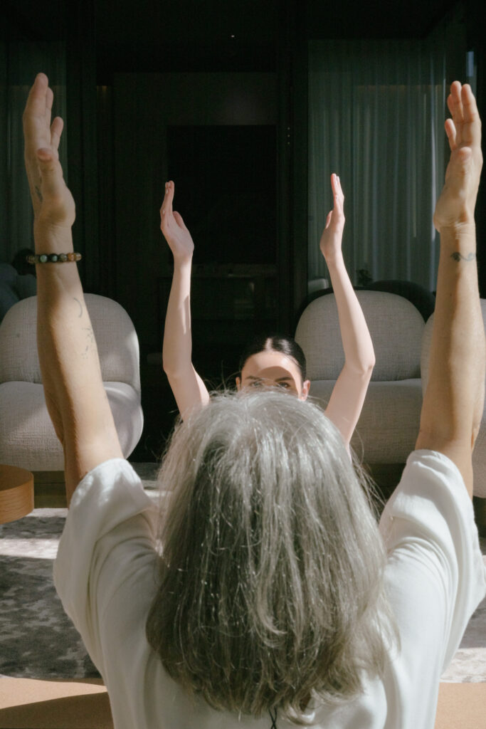 2 woman meditating, with their arms in the air