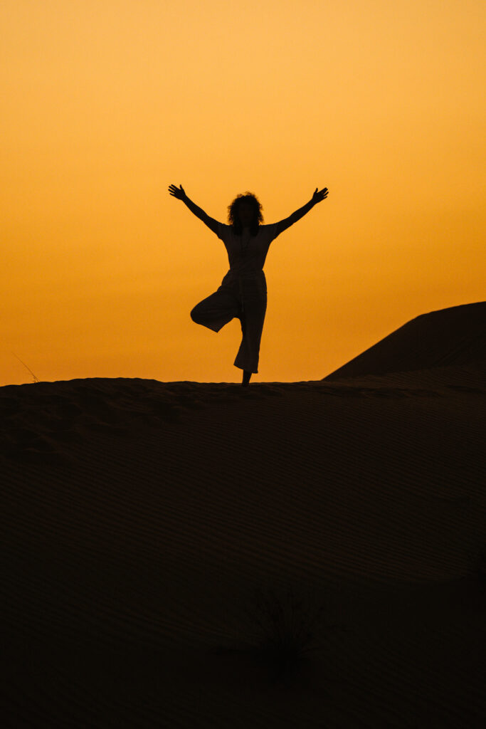 Woman meditating on the beach and you can see the sunrise in the background